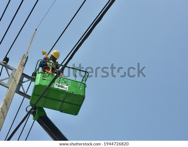 Electrician working at height in basket car on blue\
sky,construction\
site.
