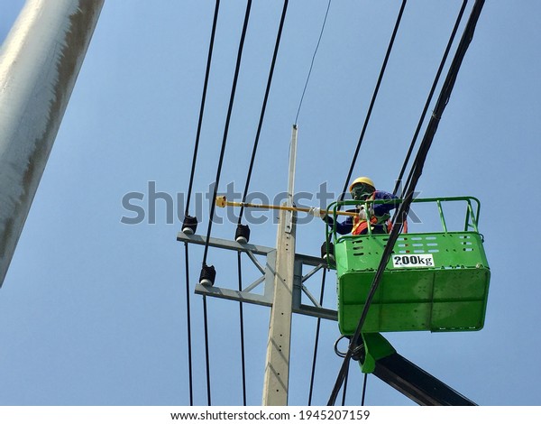 Electrician working at height in basket car on blue\
sky,construction\
site.