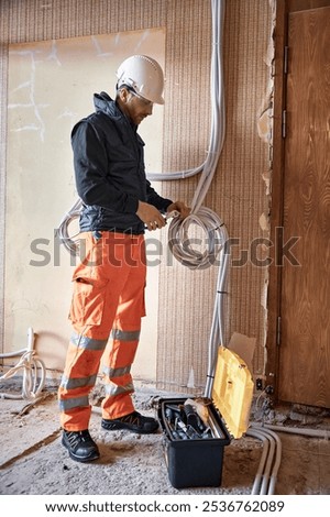 Electrician working with multiple cables during installation precess on construction site.