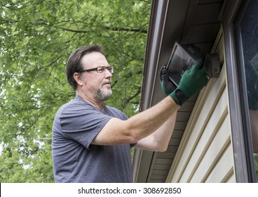 Electrician Working On Exterior Light On A  Older Home. 