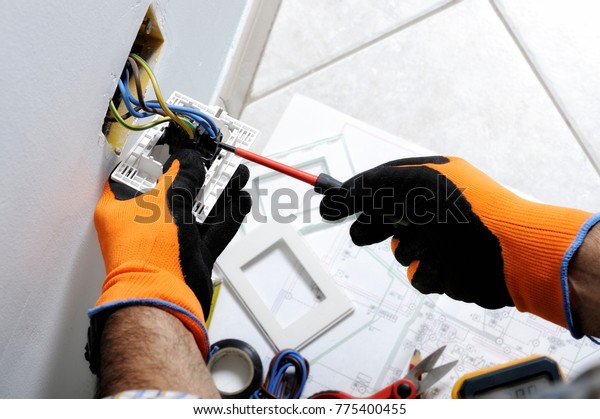 Electrician working safely on switches and sockets\
of a residential electrical\
system