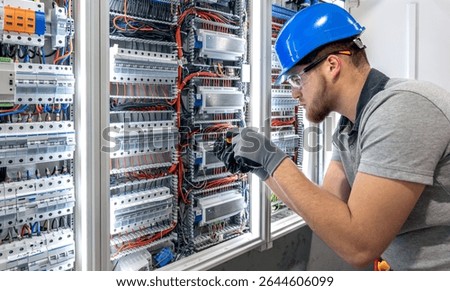 Electrician working in switchboard. Electrical component setup. Cable connection.
