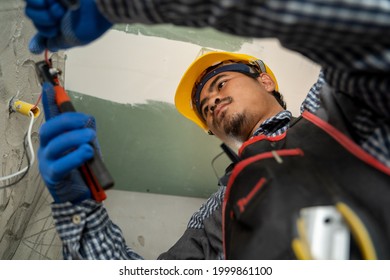 Electrician working with switches and sockets of a residential electrical system,Connects the equipment with tools,Builder. - Shutterstock ID 1999861100