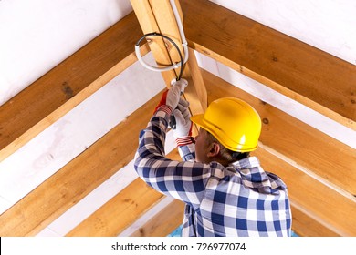 Electrician working with wires at attic renovation site