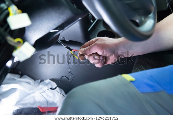 Electrician works with electric block in car. Close-up\
of automobile inside under raised hood. Service man hands working\
with cables of auto\
.