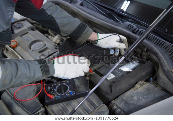 Electrician works with electric block in car. Close-up\
of automobile inside under raised hood. Service man hands working\
with cables of auto\
.