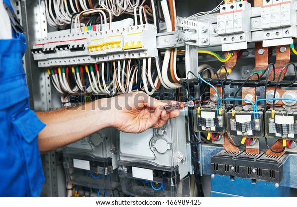 electrician\
works with electric meter tester in fuse\
box