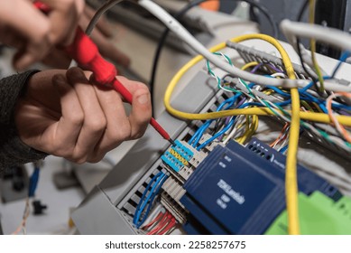 Electrician works with a screwdriver at power connections - Shutterstock ID 2258257675