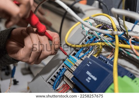 Electrician works with a screwdriver at power connections