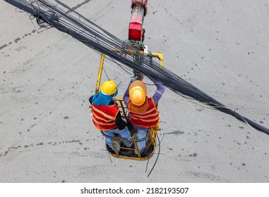 A electricians at assembly platform repair cables over the road. Installation of cables above the street of city. - Shutterstock ID 2182193507