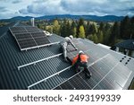 Electricians building photovoltaic solar module station on roof of house. Men technicians in helmets installing solar panel system outdoors. Concept of alternative and renewable energy. Aerial view.