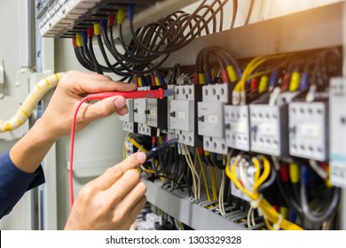 Electricians hands testing current  electric in control panel. - Shutterstock ID 1303329328