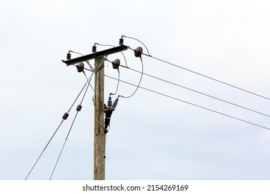 Electricity cables fixed to a wooden poll with a blue sky background
