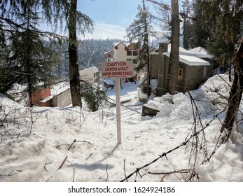 Electricity caution board and snow fall covered city.