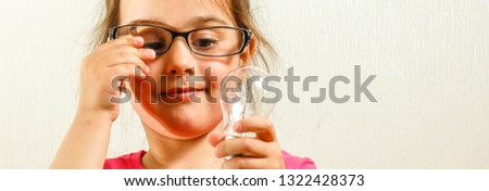 Electricity, education and people concept - smiling little girl holding light bulb