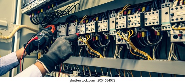 Electricity And Electrical Maintenance Service, Close-up Circuit Breaker Has Engineer Using Measuring Equipment Checking Electric Volt At Terminal Block And Cable Wiring Main Power Distribution Board.