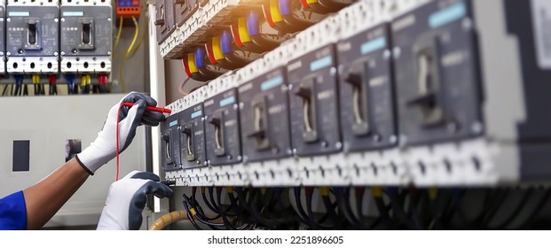 Electricity or electrical maintenance service, Electrician hand checking electric current voltage at circuit breaker terminal and cable wiring check in main power load center distribution board. - Shutterstock ID 2251896605