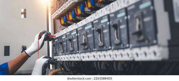 Electricity or electrical maintenance service, Electrician hand checking electric current voltage at circuit breaker terminal and cable wiring check in main power load center distribution board. - Shutterstock ID 2261088405