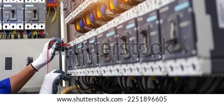 Electricity or electrical maintenance service, Electrician hand checking electric current voltage at circuit breaker terminal and cable wiring check in main power load center distribution board.
