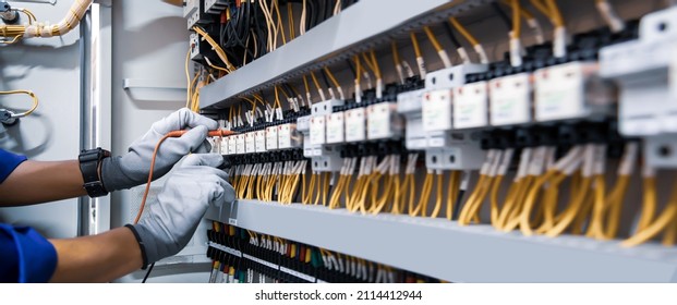 Electricity and electrical maintenance service, Engineer using measuring equipment tool checking electric current voltage at circuit breaker terminal and cable wiring main power distribution board. - Shutterstock ID 2114412944