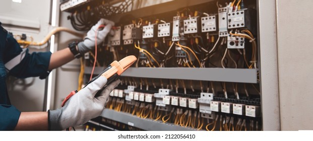 Electricity and electrical maintenance service, Engineer using measuring equipment tool checking electric current voltage at circuit breaker terminal and cable wiring main power distribution board.