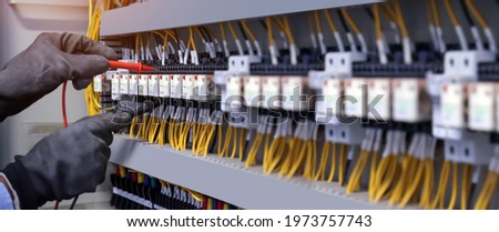 Electricity and electrical maintenance service, Engineer checking electric at circuit breaker and cable wiring system for repairing main power distribution board.