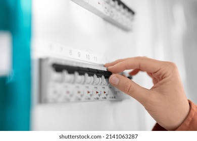 Electricity, Energy And Power Consumption Concept - Close Up Of Hand Switching Electric Board At Home