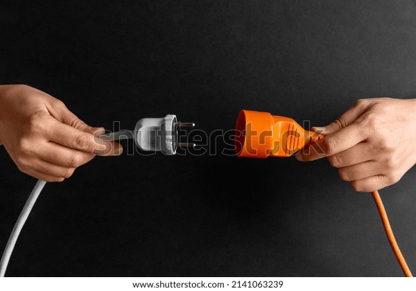 electricity,\
energy and power consumption concept - close up of woman inserting\
plug into socket over black\
background