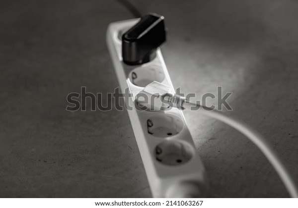 electricity, energy\
and power consumption concept - close up of socket with plugs and\
charger on concrete\
floor