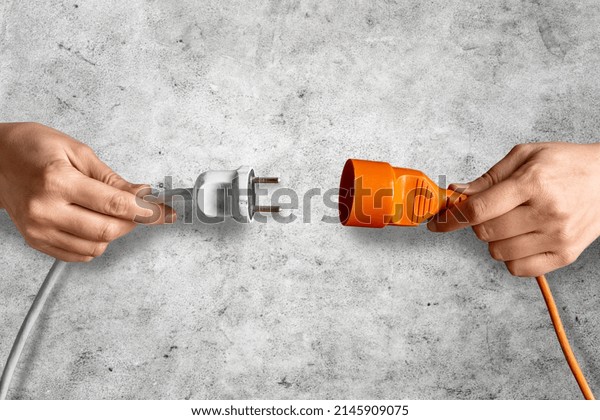 electricity,\
energy and power consumption concept - close up of woman inserting\
plug into socket over concrete\
background