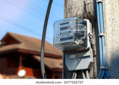 An electricity meter is installed on a light pole in front of the house to measure the amount of electricity used in the house.                              