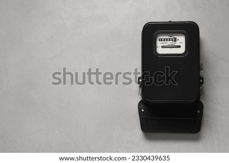Electricity meter on light grey wall, space for text