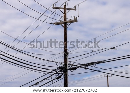 Electricity pole with many electrical cables. Complex power grid wooden poles connecting and distributing electricity and TV signals.