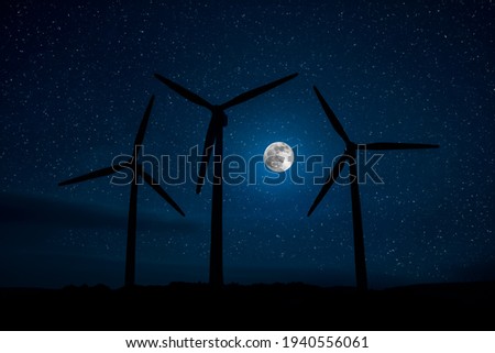 Electricity power in nature or clean energy concept. Wind Turbine producing alternative energy on hill at night. Creative decoration with small miniature. Selective focus
