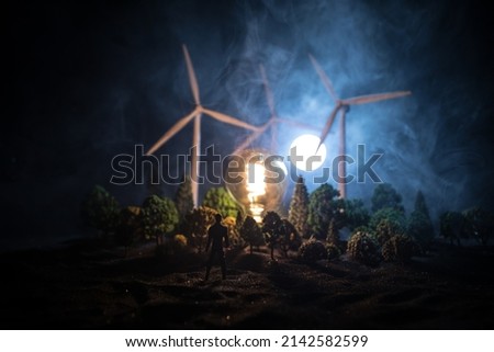 Electricity power in nature or clean energy concept. Wind Turbine producing alternative energy at night. Glowing bulb powered by alternative energy. Selective focus