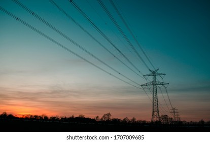 Electricity Pylon On Fields At Sunset