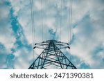 Electricity pylon with overhead powerline cables against cloudy sky, low angle view