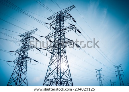 electricity transmission pylon silhouetted against blue sky at dusk 