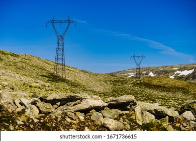 Electricity transmission pylons, power lines high voltage towers in norwegian mountains landscape.