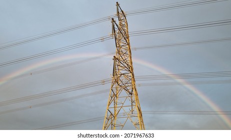 Electricty pylon carying high voltage cables with a rainbow in the background.