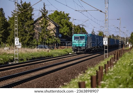 An electrified freight train passing through a rural landscape in Germany
