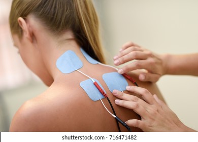 Electro stimulation in physical therapy to a young woman. Medical check at the shoulder in a physiotherapy center. - Shutterstock ID 716471482