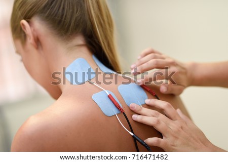 Electro stimulation in physical therapy to a young woman. Medical check at the shoulder in a physiotherapy center.
