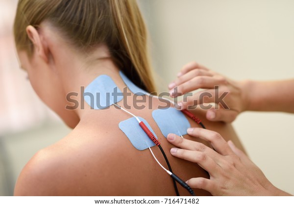 Electro\
stimulation in physical therapy to a young woman. Medical check at\
the shoulder in a physiotherapy\
center.