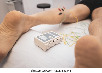 electroacupuncture with the needle connection machine used by the acupuncturist in men. Electrical stimulation in physiotherapy to the twin of a young man in the physiotherapy center.