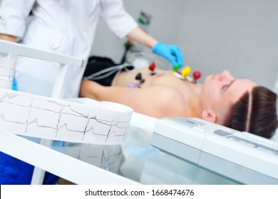 Electrocardiogram, ECG in hand. Clinic of Cardiology heart rate and pulse test closeup. Cardiogram printout on a male patient background