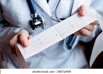 Electrocardiogram, Ecg In Hand, Palm Of A Doctor. Medical Health Care. Clinic Cardiology Heart Rhythm And Pulse Test Closeup. Cardiogram Printout. 