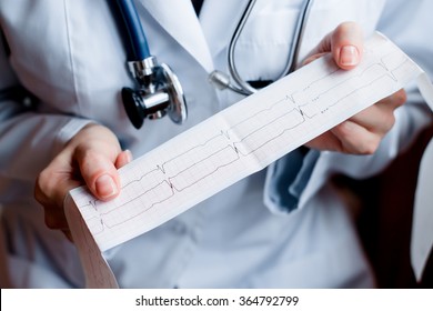 Electrocardiogram, ecg in hand, palm of a doctor. Medical health care. Clinic cardiology heart rhythm and pulse test closeup. Cardiogram printout. 