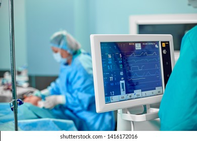 Electrocardiogram in hospital surgery operating emergency room showing patient heart rate with blur team of surgeons background