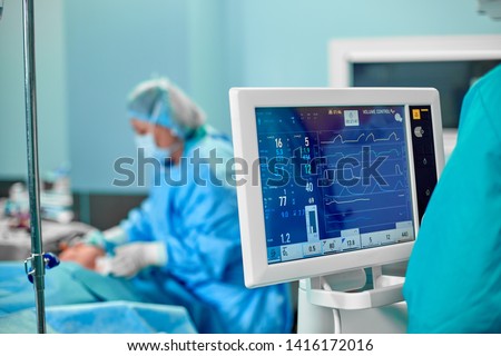 Electrocardiogram in hospital surgery operating emergency room showing patient heart rate with blur team of surgeons background